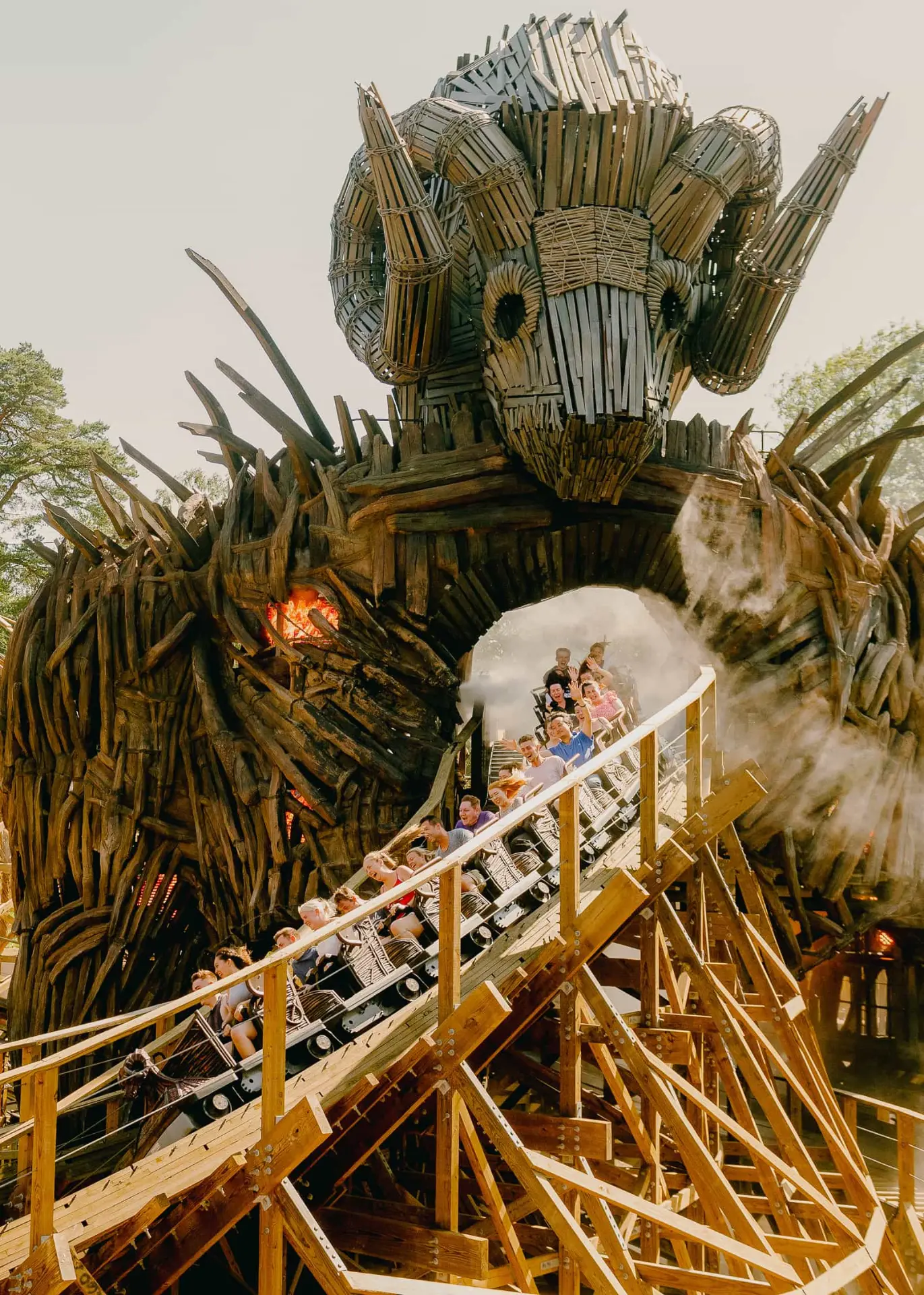 Guests riding a wooden coaster through a large dragon-themed structure.