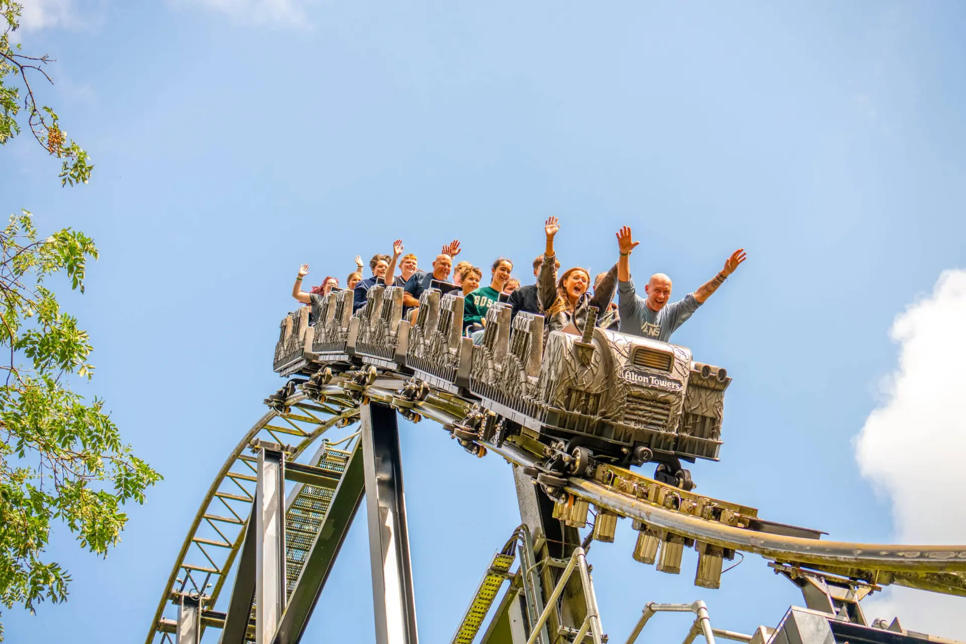 Riders throwing their hands up on Nemesis in the summer sun — Alton Towers in Staffordshire, England