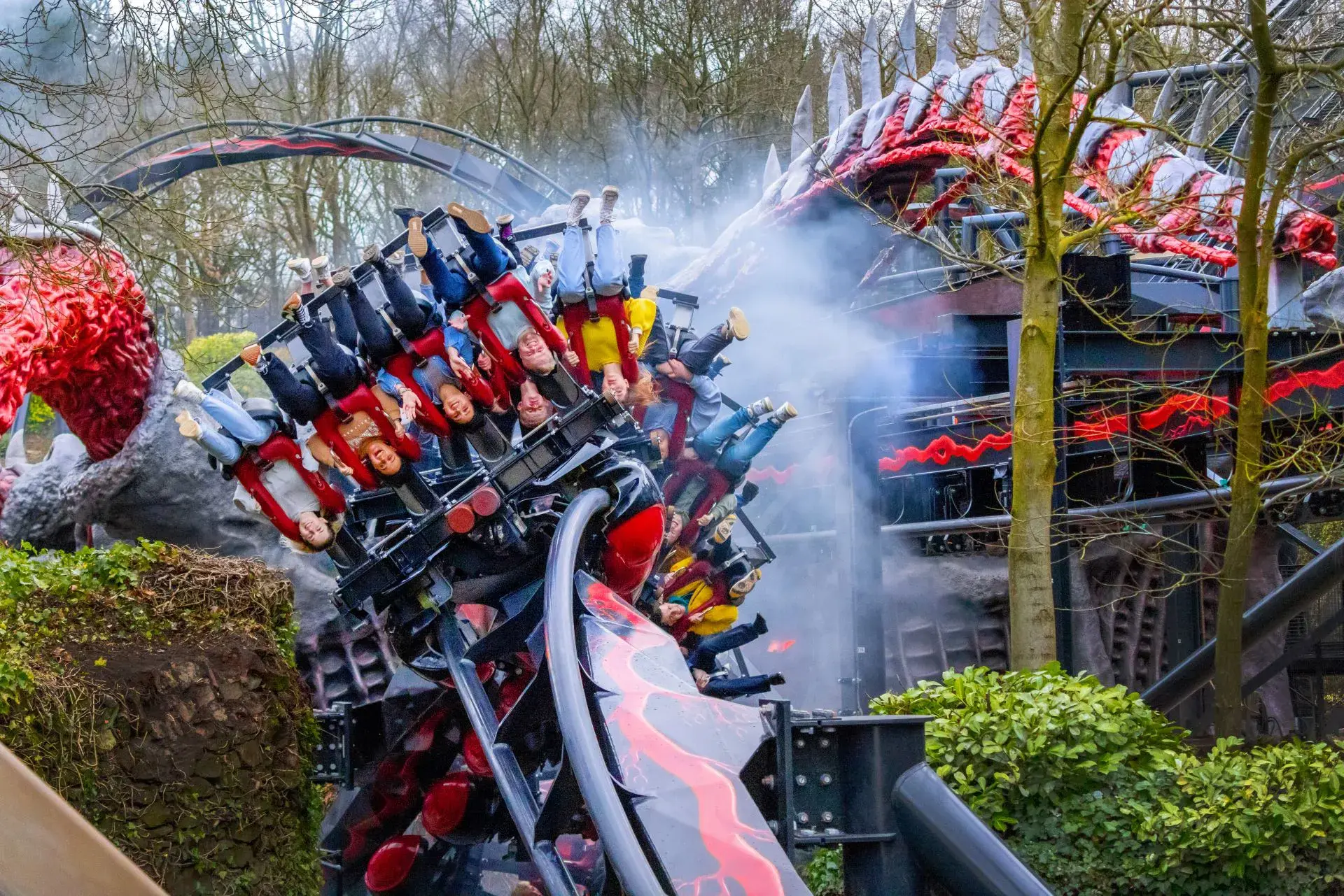Guests riding a red-and-black inverted coaster with a dragon-themed train.