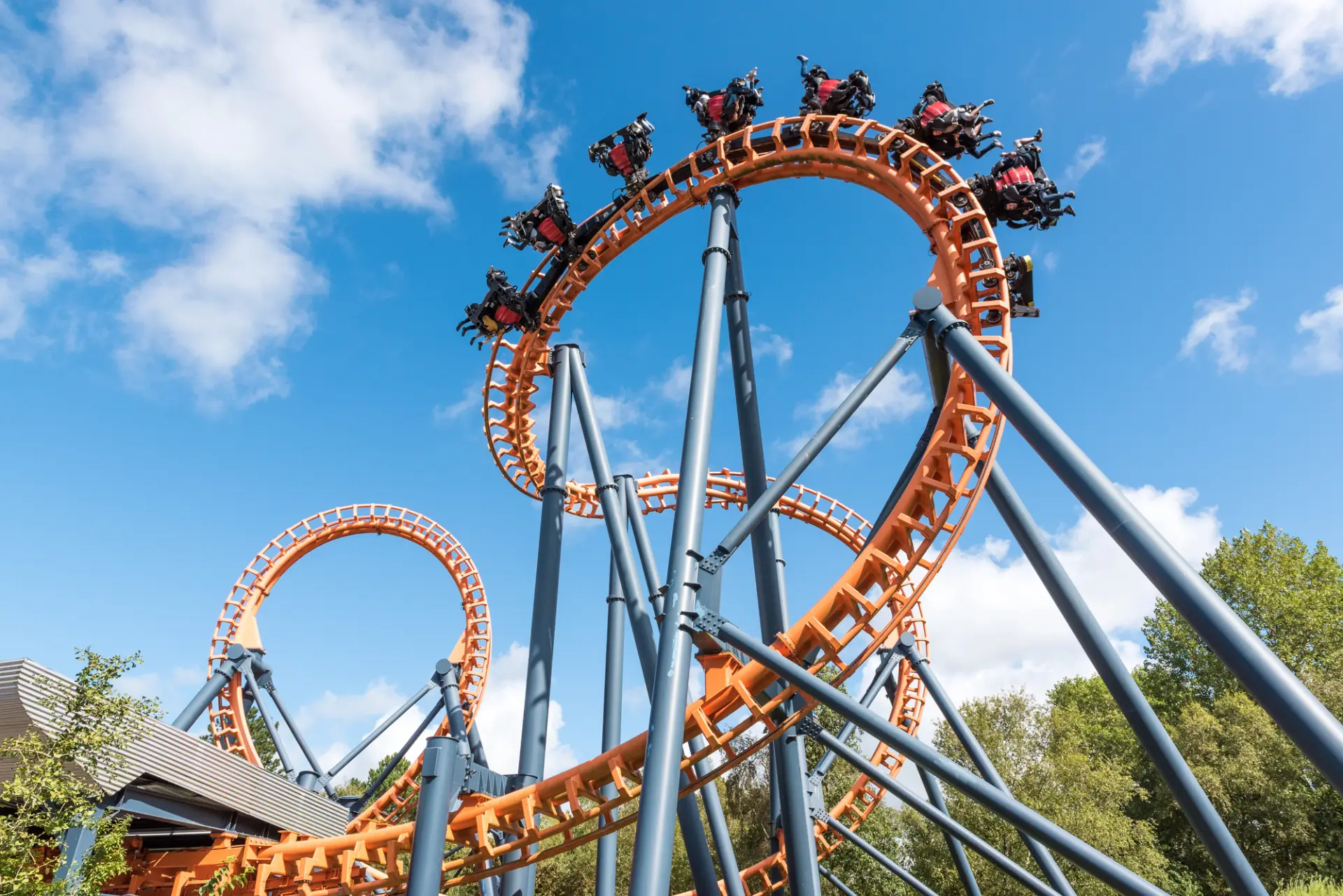 Riders on an intense orange looping roller coaster