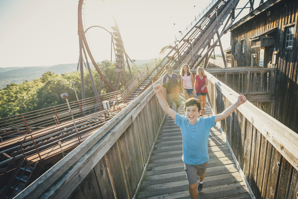 A family crossing the boardwalk beneath Wildfire's loop — Silver Dollar City in Branson, Missouri